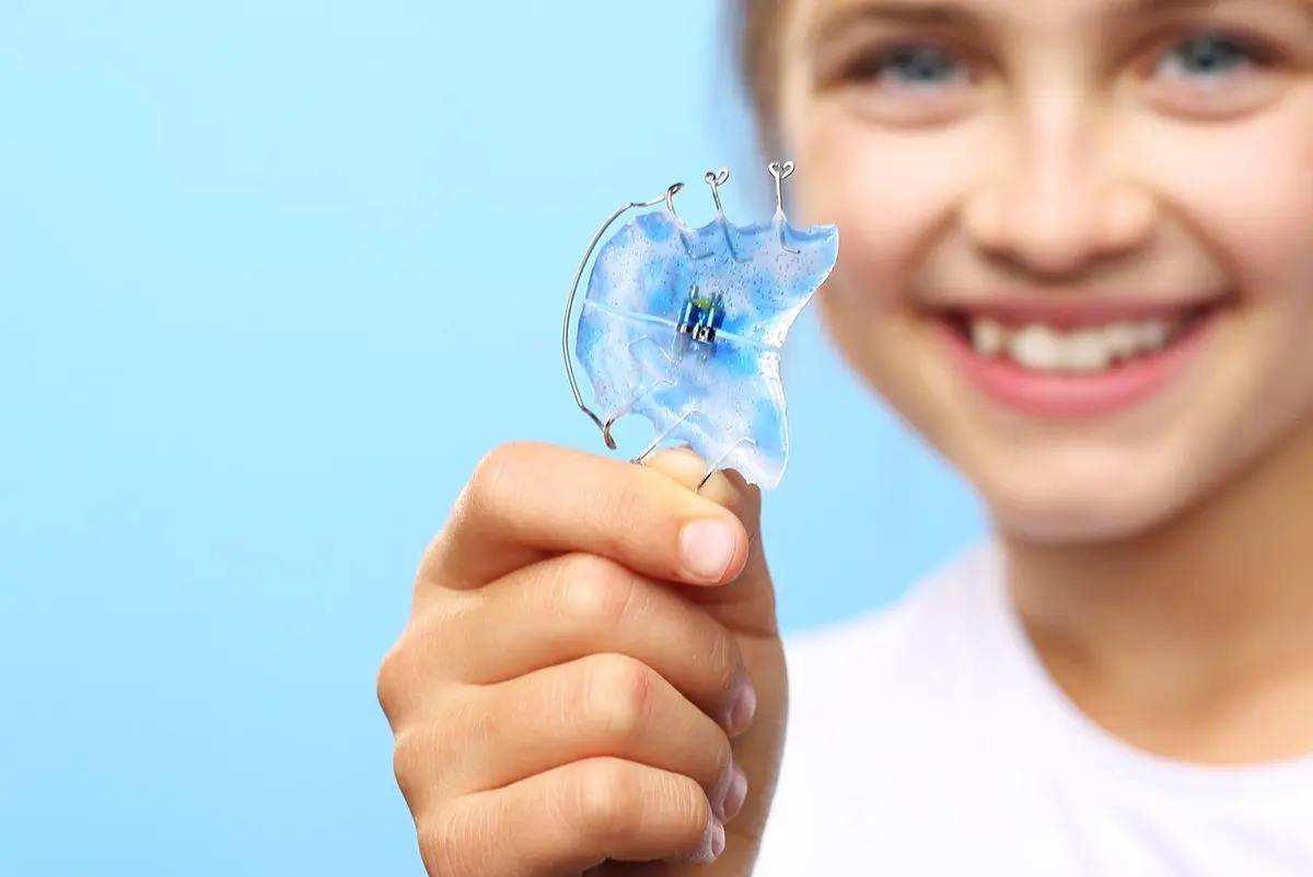 Hawley retainer is an alternative to a permanent retainer girl holding her blue Hawley retainer after Beverly Hills Ortho Treatment