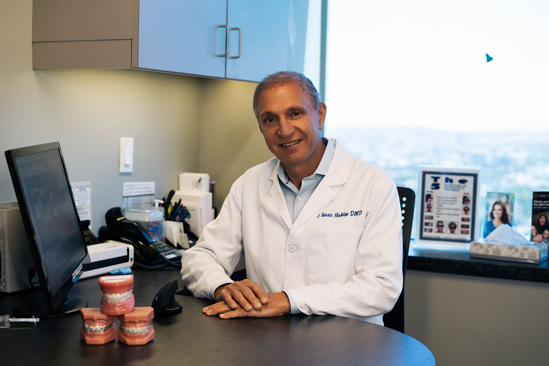 Dr. F Isaac Hakim, the orthodontist at the Orthospaceship, sitting at his desk as he creates the best orthodontic treatment plans for his patients in Los Angeles