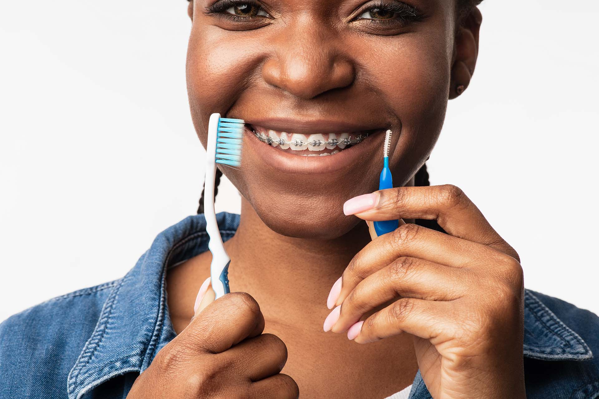 Young girl holding a toothbrush and proxy brush as she learns how to care for braces, your dental appliances