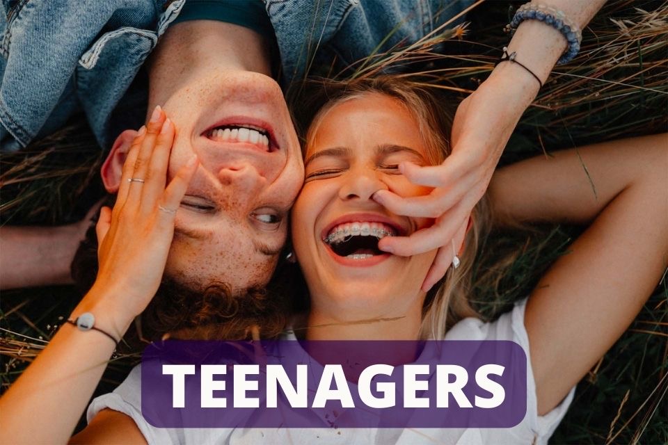 A teenage couple laying head to head holding each other's face as the teen girl wears accelerated braces from the best orthodontists at Hakim Orthodontics near Beverly Crest, Los Angeles