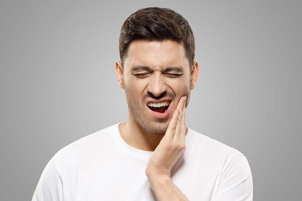 Man rubbing his upper and lower teeth that are in pain from tmj disorder