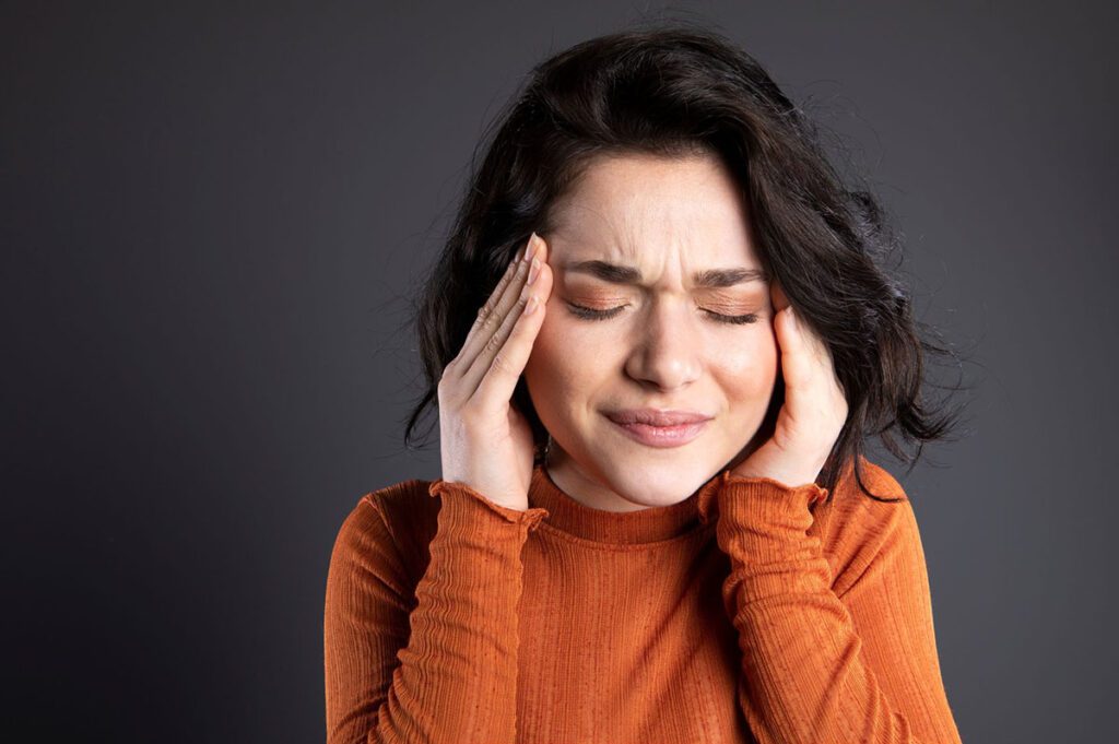 Woman rubbing her head in pain due to TMJ disorder