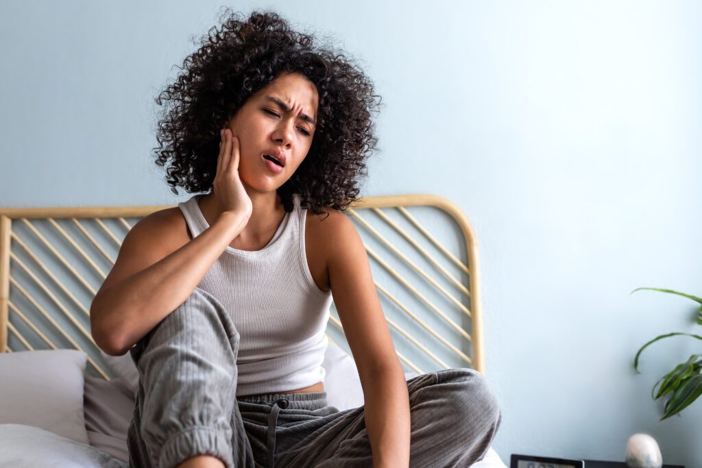 Woman holding jaw due to TMJ pain