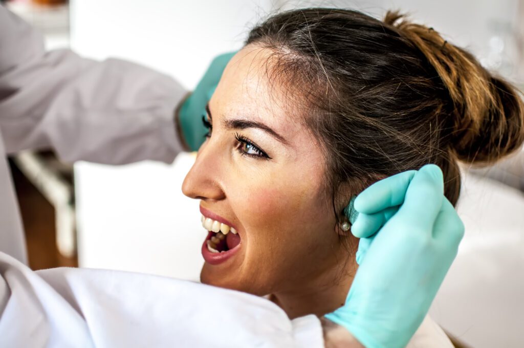 Woman getting TMJ exam by orthodontist specializing in TMJ treatment