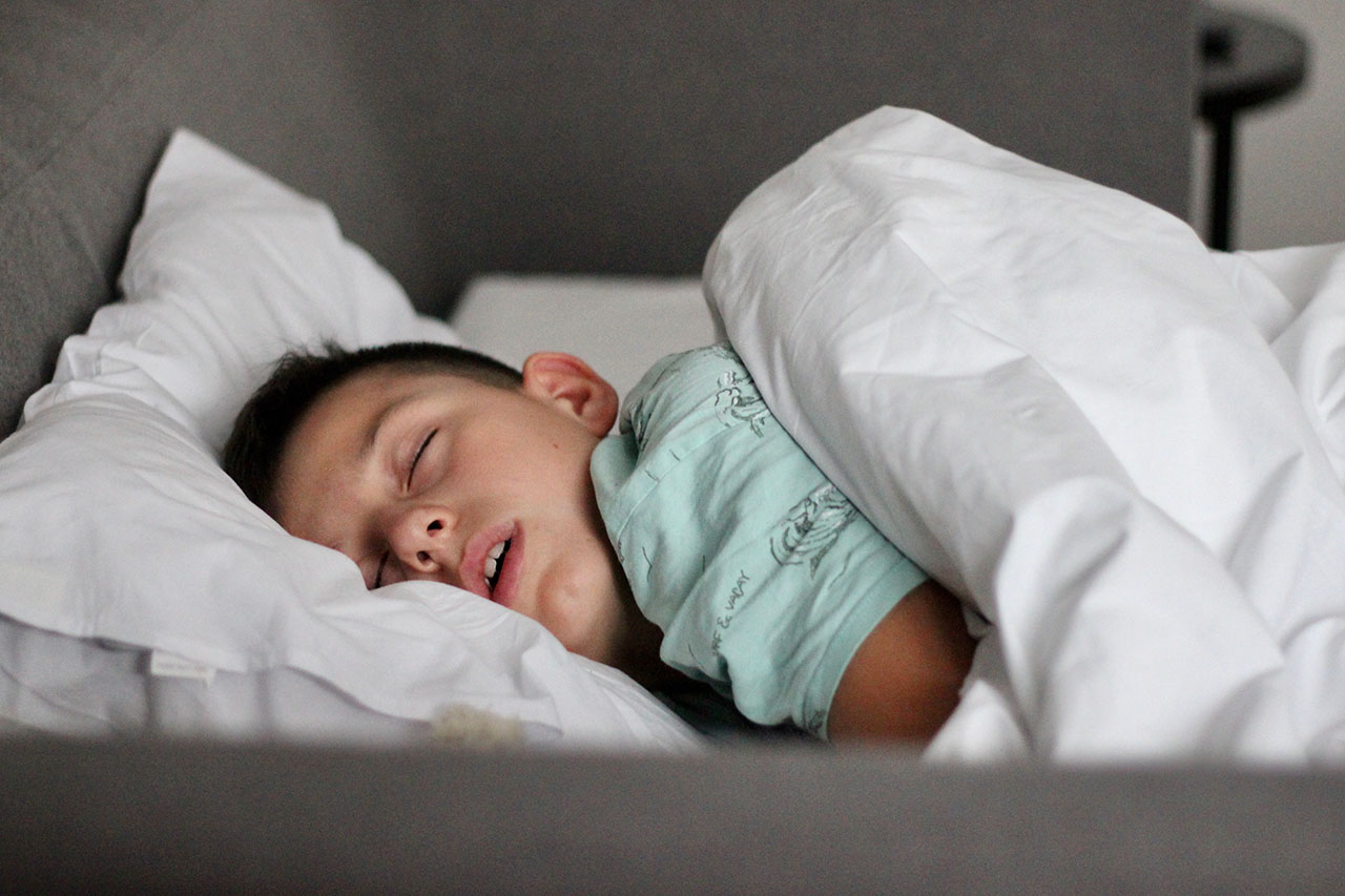 child sleeping in bed with his mouth open