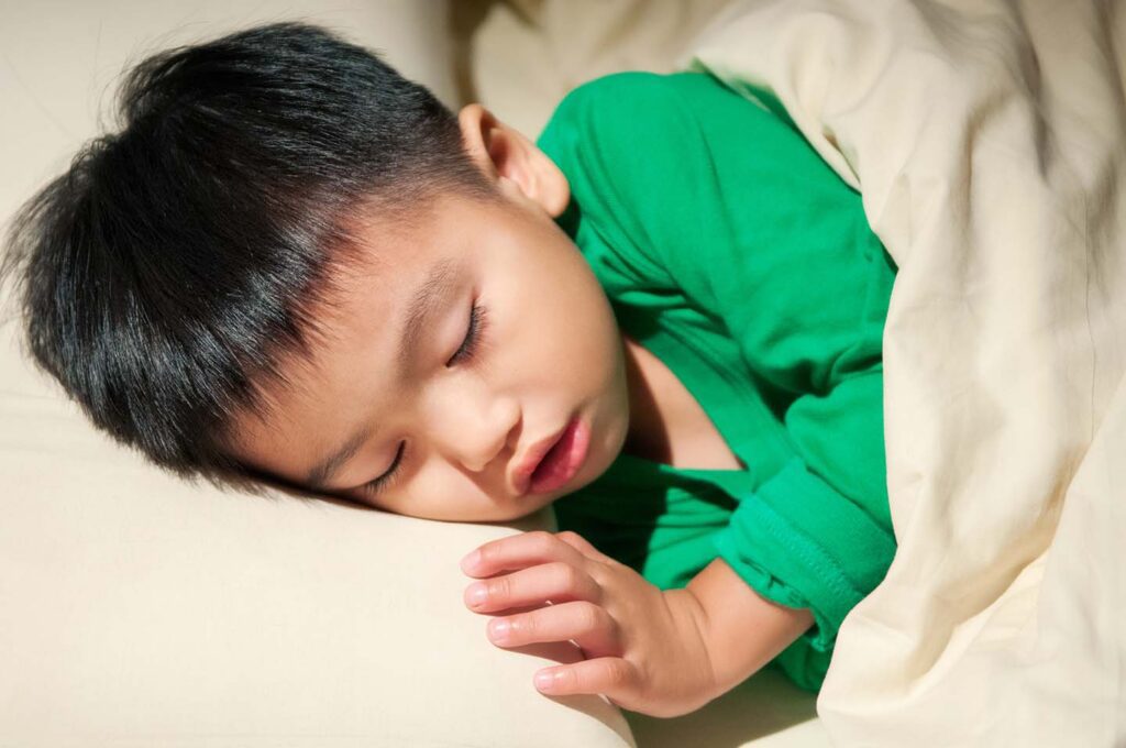 young boy fast asleep in his bed